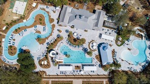 Vista aérea de un resort con varias piscinas, tumbonas y una gran edificación.
