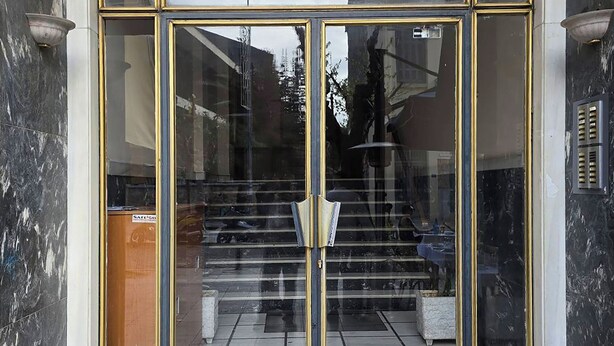 A building entrance with a glass door and a staircase leading inside. - Acropolis Hideaway Studio by GHH (Athina)