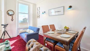 En matplats med ett bord dukat för fyra personer, en blå soffa och ett stativ med ett kamerahuvud.