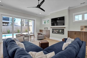 Uma sala de estar moderna com um sofá modular, uma televisão de tela plana e uma lareira.