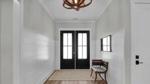 A hallway with a wooden floor, a bench, a rug, and a door with a mirror above it. - Brezza Fresca w/ a private pool In Carolina Beach (Wilmington)