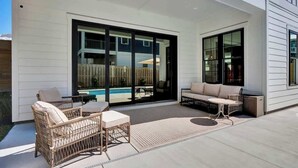 A covered patio with wicker furniture, a pool, and a sliding glass door. - Brezza Fresca w/ a private pool In Carolina Beach (Wilmington)