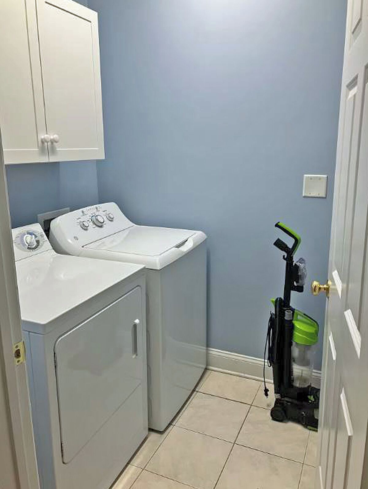 Una sala de lavandería con lavadora, secadora y una máquina de limpieza verde.