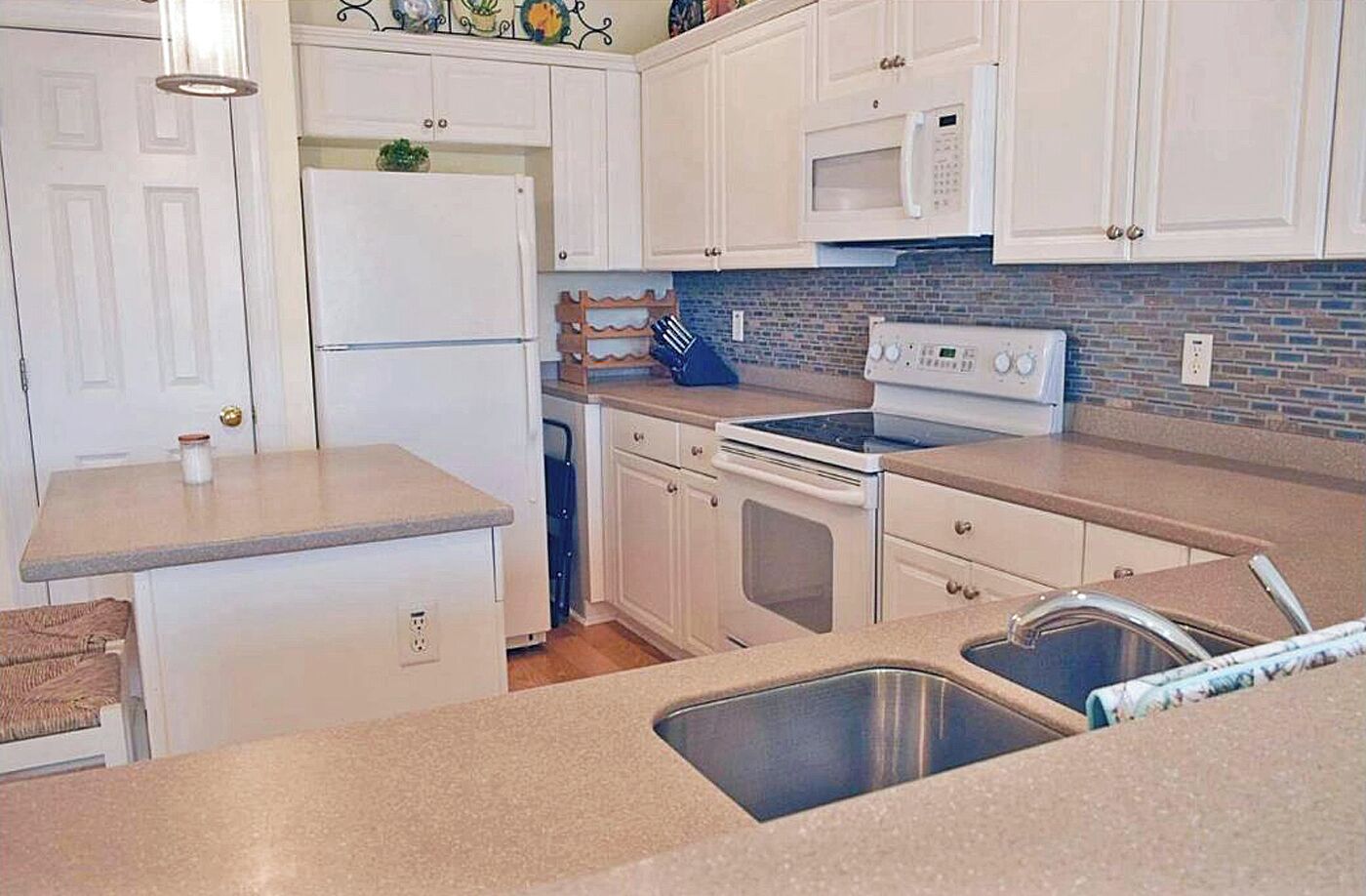 A compact kitchen with white cabinets, a microwave, a stove, and a sink.