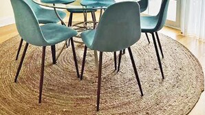 Un comedor con una mesa redonda, seis sillas, una araña y vistas a través de un ventanal.