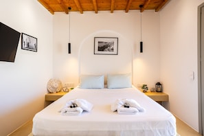 Ein ordentlich eingerichtetes Hotelzimmer mit einem Bett, zwei Nachttischen, einem an der Wand hängenden Bild und einer Decke mit Holzbalken.