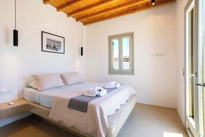 Un dormitorio con una cama, una ventana, un cuadro en la pared y techo de madera.