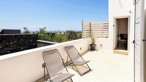 Una terraza en la azotea con dos sillones, una planta en maceta y vistas al mar.