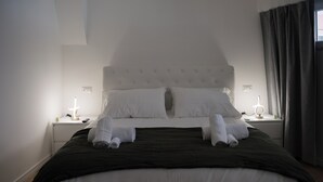 Una cama bien hecha con sábanas blancas y dos lámparas de noche.