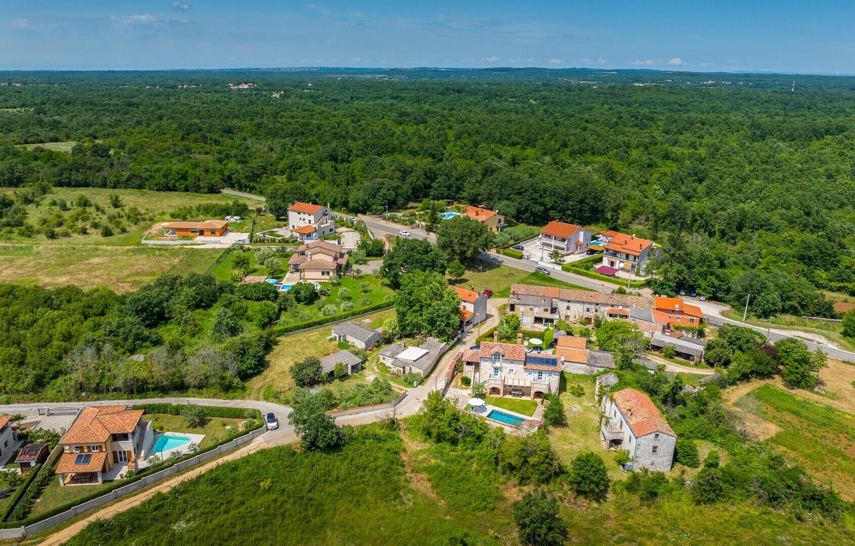 An aerial view of a residential area with houses, roads, and greenery.