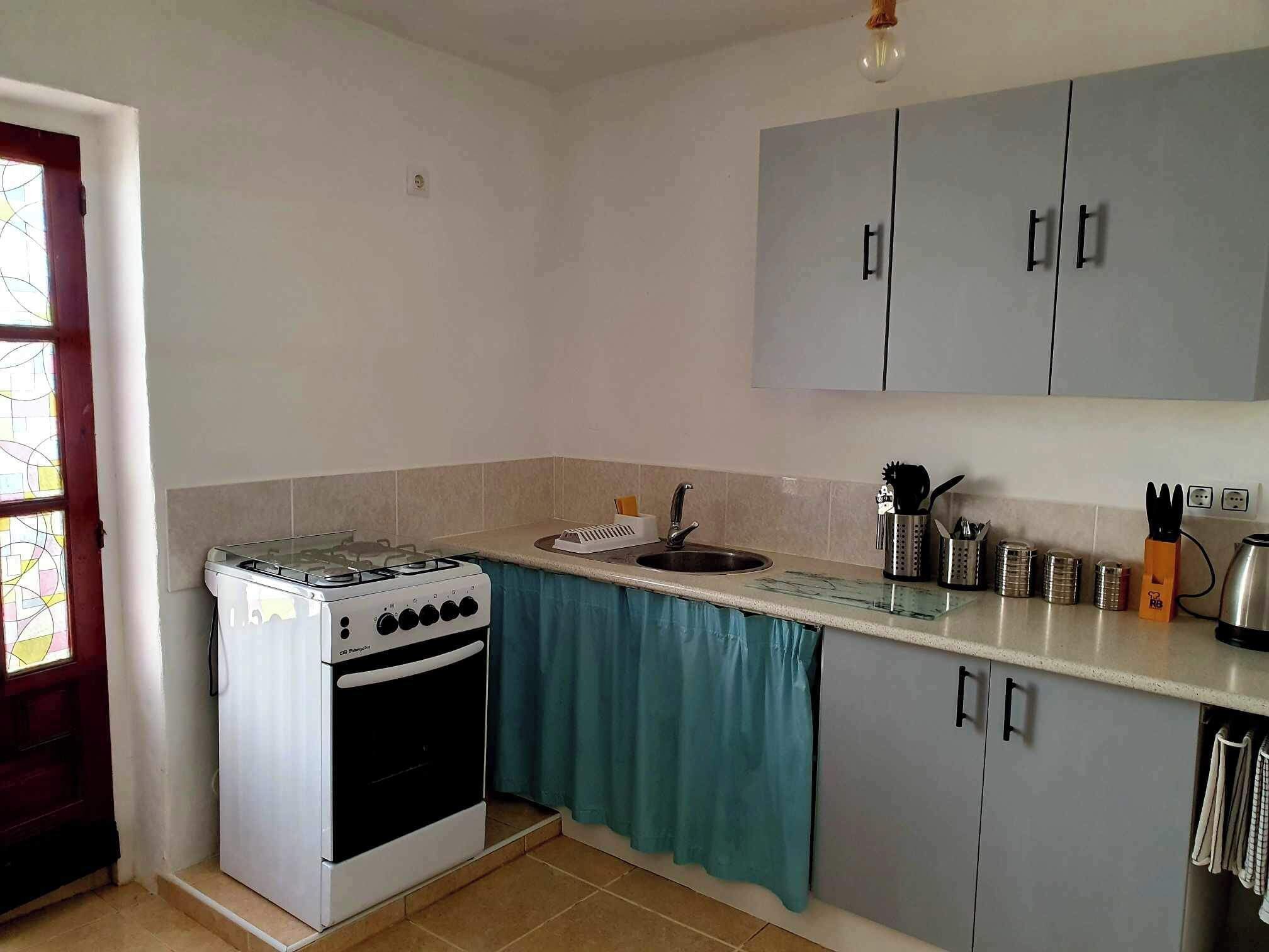 A compact kitchen with a gas stove, a sink, and grey cabinets.