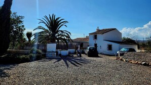 A gravel driveway leading to a white house with a tiled roof, a parked car, and a motorcycle. - Casita-1 To 5guests-pool-patio-bbq-parking (Huercal-Overa)