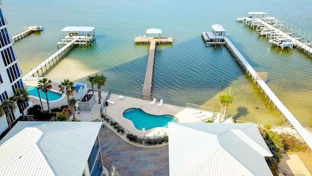 A marina with docked boats, a swimming pool, and a pier extending into the water.