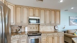 Eine Küche mit hellen Holzschränken, Edelstahlgeräten und einer gefliesten Spritzschutzwand.