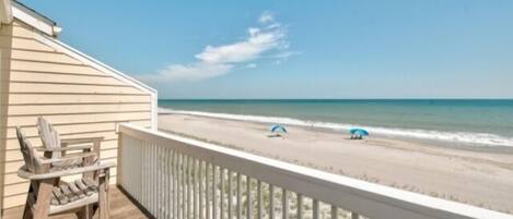 A wooden deck with a view of the beach and ocean.