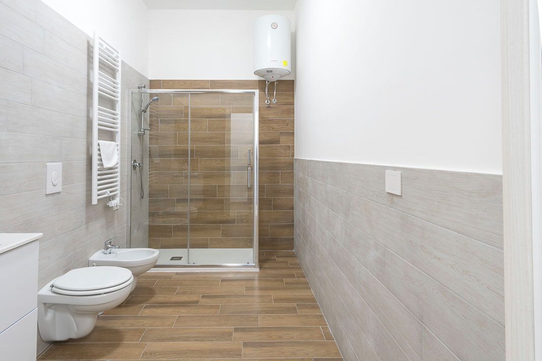 A modern bathroom with a glass shower enclosure, a white toilet, and a bidet.