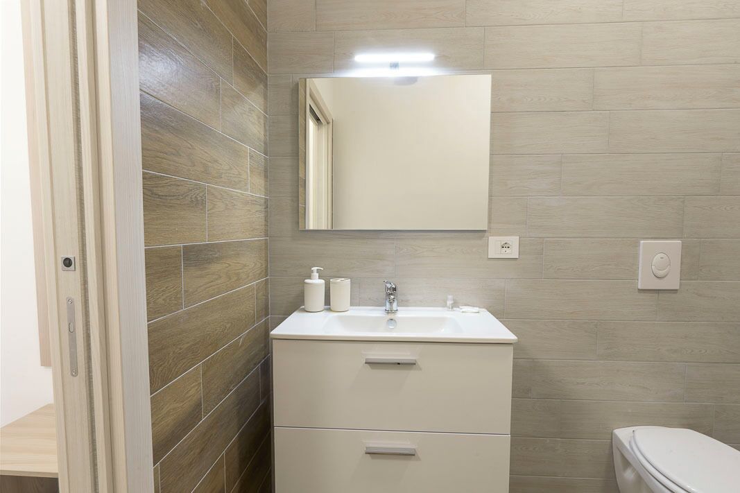 Un baño con un tocador blanco, un espejo y un inodoro.