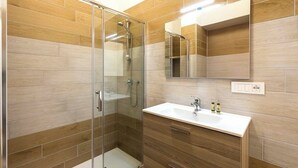 A modern bathroom with a glass shower enclosure, a wooden vanity, and a mirror above the sink. - Malcangi 29 (Trani)