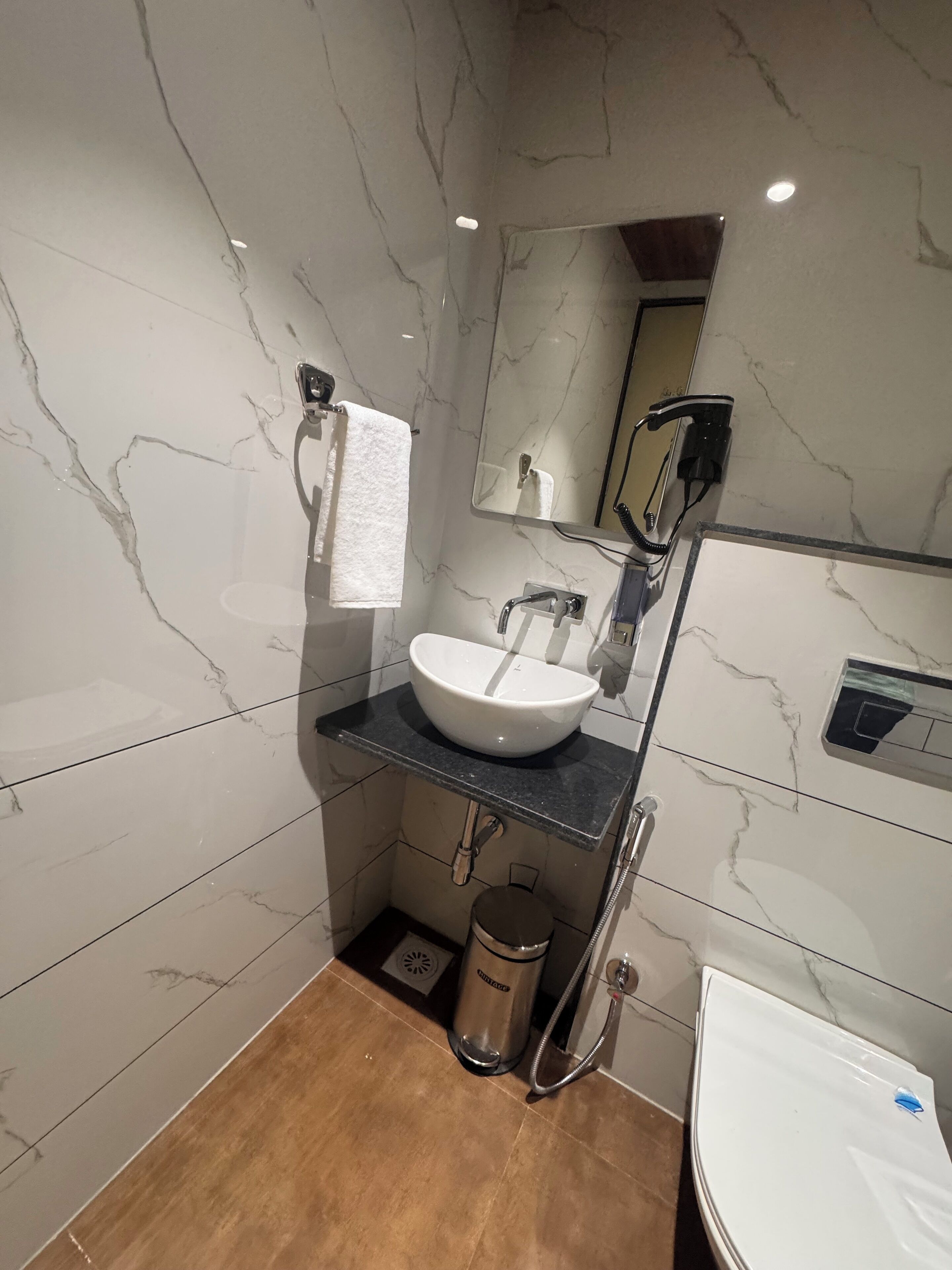 Un baño moderno con lavamanos de mármol, cabezal de ducha de mano y retrete.