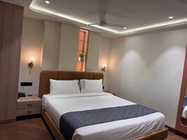 Un dormitorio moderno con cabecera de madera, cama grande con colcha acolchada, lámparas de noche, mesita de noche y ventilador de techo.