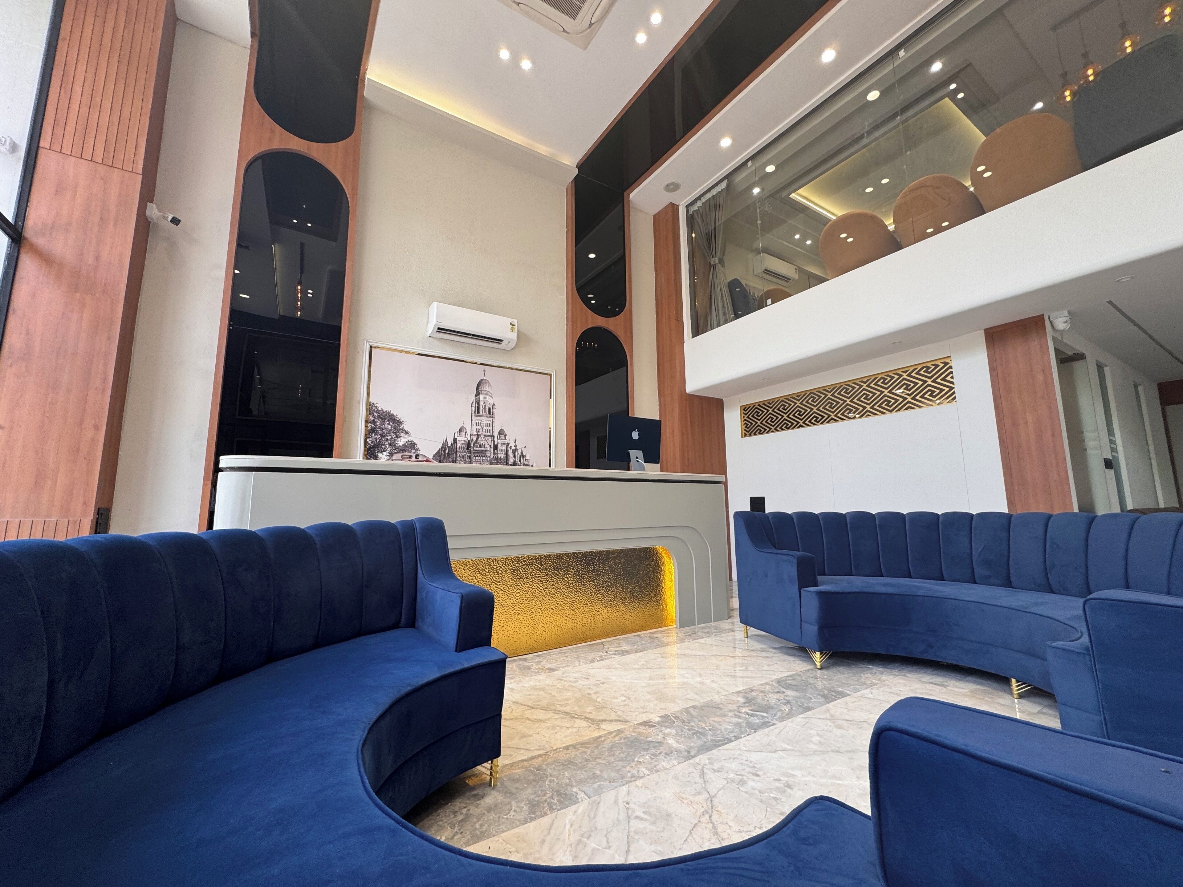 A modern lobby with blue sofas, a reception desk, and a large window.