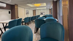 A conference room with rows of teal chairs, a long table, and a ceiling with recessed lighting and a skylight.