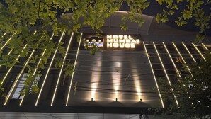 A hotel entrance with a modern design, featuring a textured column, a signboard, and a checkered pavement.