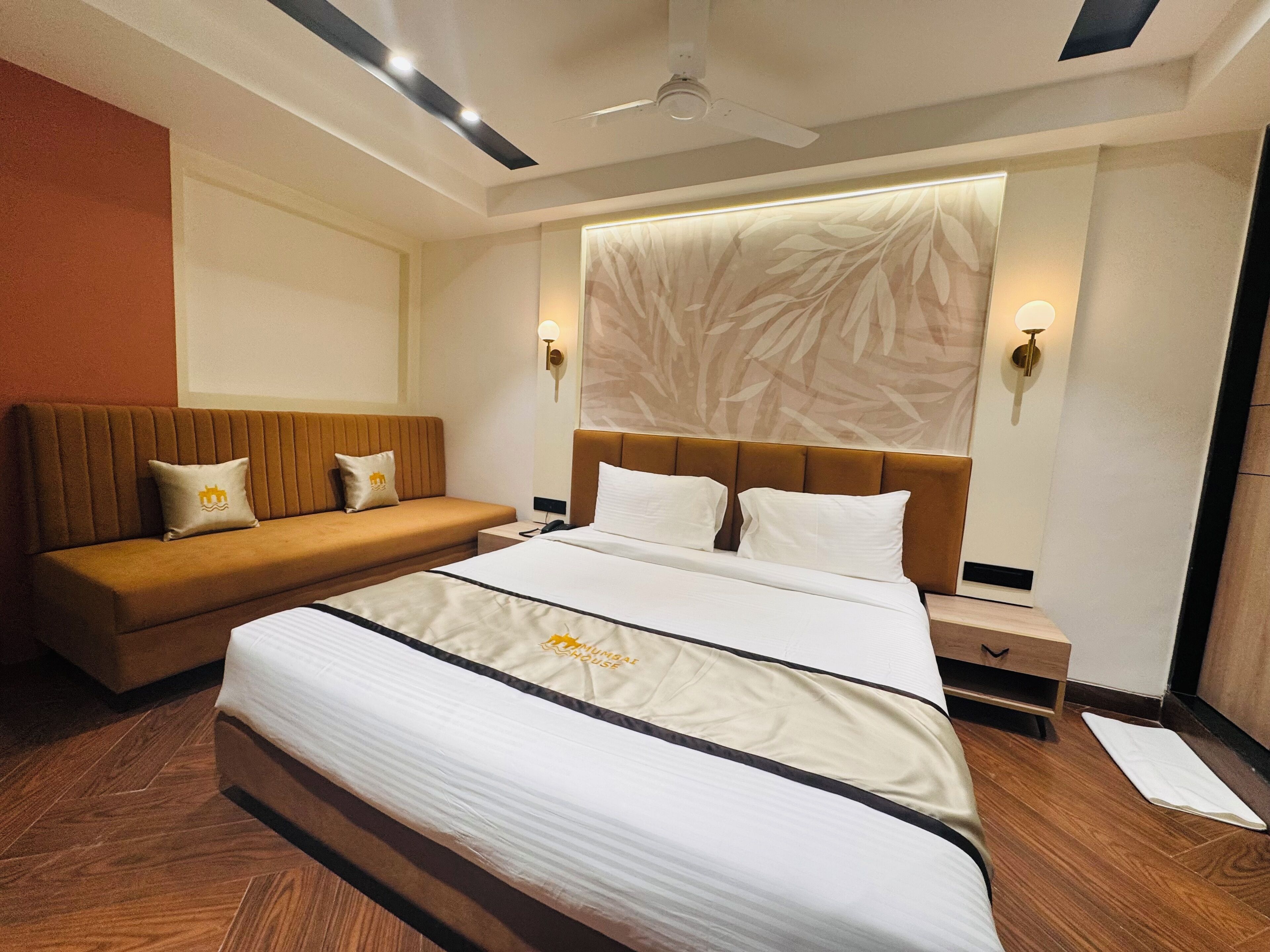 A hotel room with a large bed, a sofa, and a nightstand.