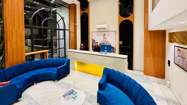 A modern lobby with blue sofas, a reception desk, and a large window.