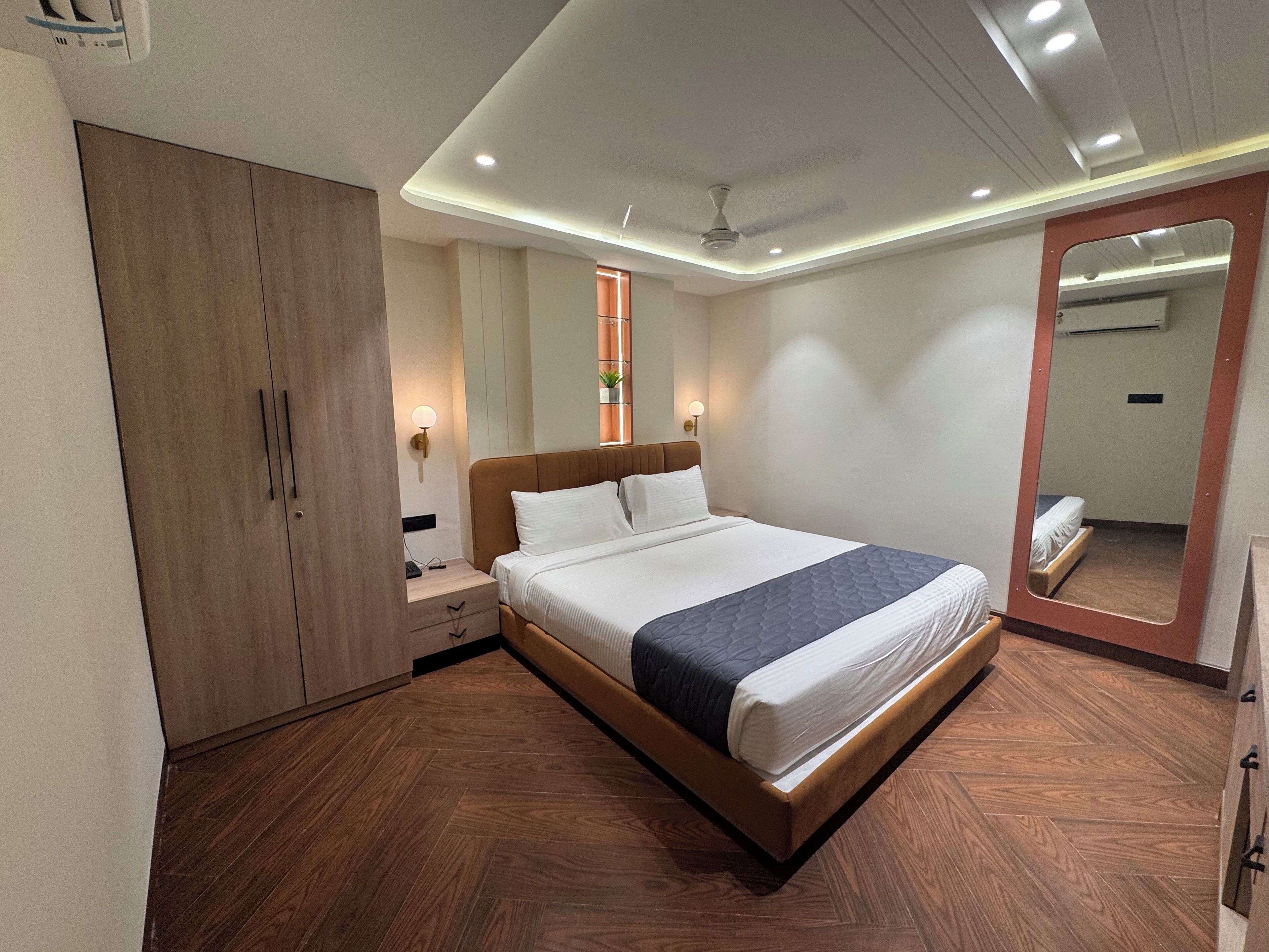 Ein modernes Schlafzimmer mit einem großen Bett, einem Holzschrank, einem Nachttisch und einem Spiegel.