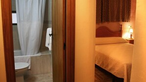 A hotel room with a bed, a nightstand with a lamp, a bathroom with a bathtub and toilet. - SINGLE ROOM IN THE MAIN SQUARE OF TRUJILLO (Trujillo)