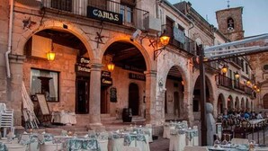 An outdoor dining area with tables set for a meal, in front of a building with arches and a sign that reads "CASAS." - SINGLE ROOM IN THE MAIN SQUARE OF TRUJILLO (Trujillo)