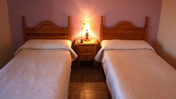 A room with two single beds, a nightstand with a lamp, and a tiled floor. - SINGLE ROOM IN THE MAIN SQUARE OF TRUJILLO (Trujillo)