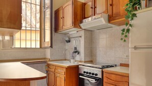 A kitchen with wooden cabinets, a stove, and a sink. - JOIVY Charming flat in Porta Romana (Milan)