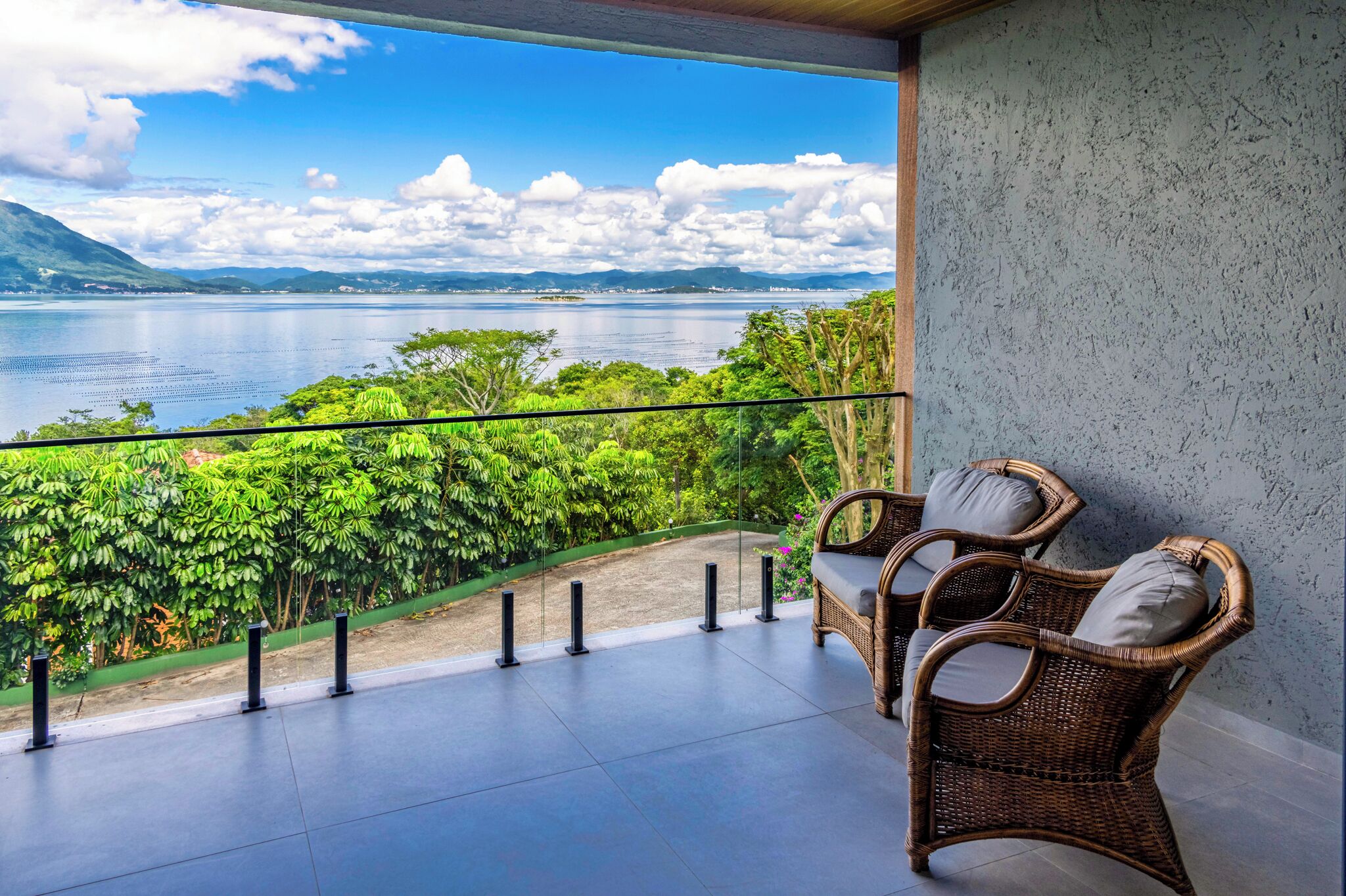Un balcón con mobiliario de mimbre y vista a un lago y montañas.