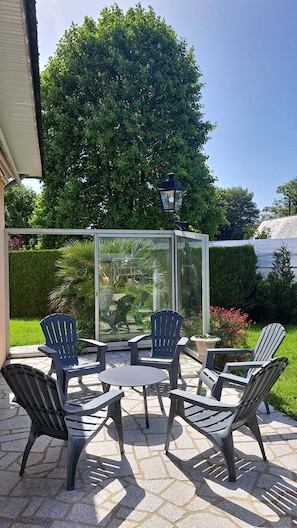 Un patio con mobiliario exterior, un cerramiento de cristal y vistas a un paisaje verde.