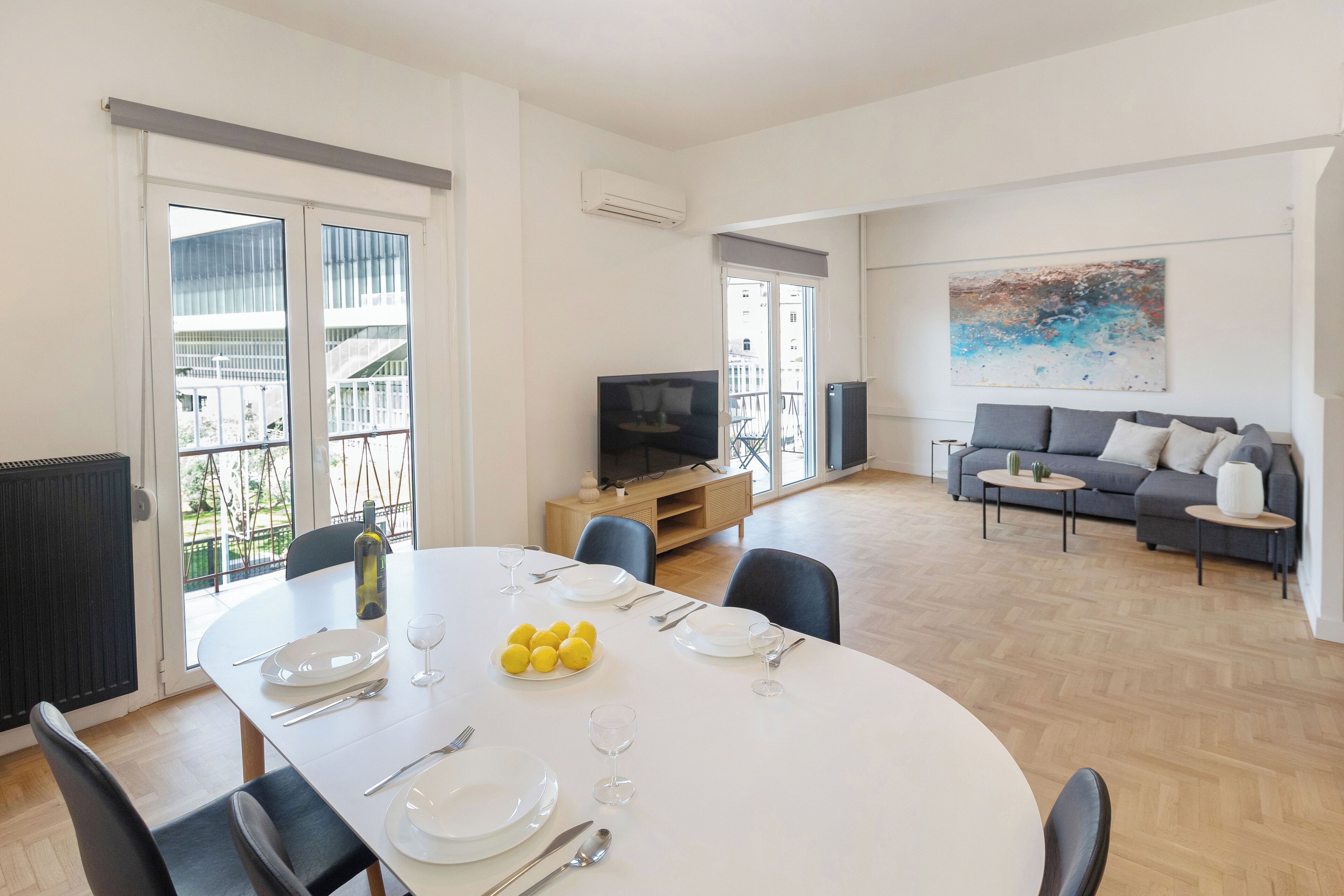 A dining area with a table set for four, a sofa, and a TV in the background.