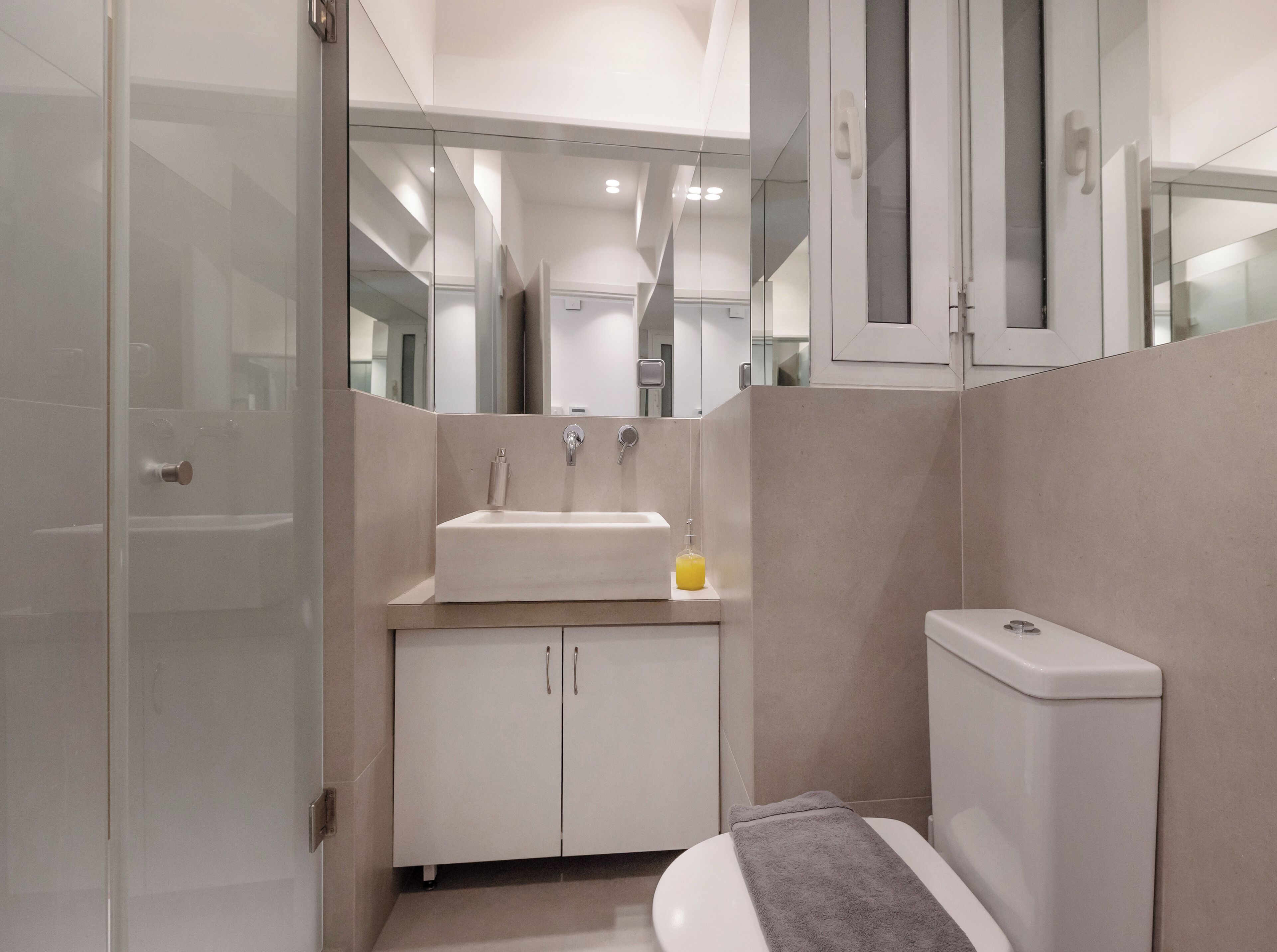 A modern bathroom with a sink, toilet, and glass shower enclosure.