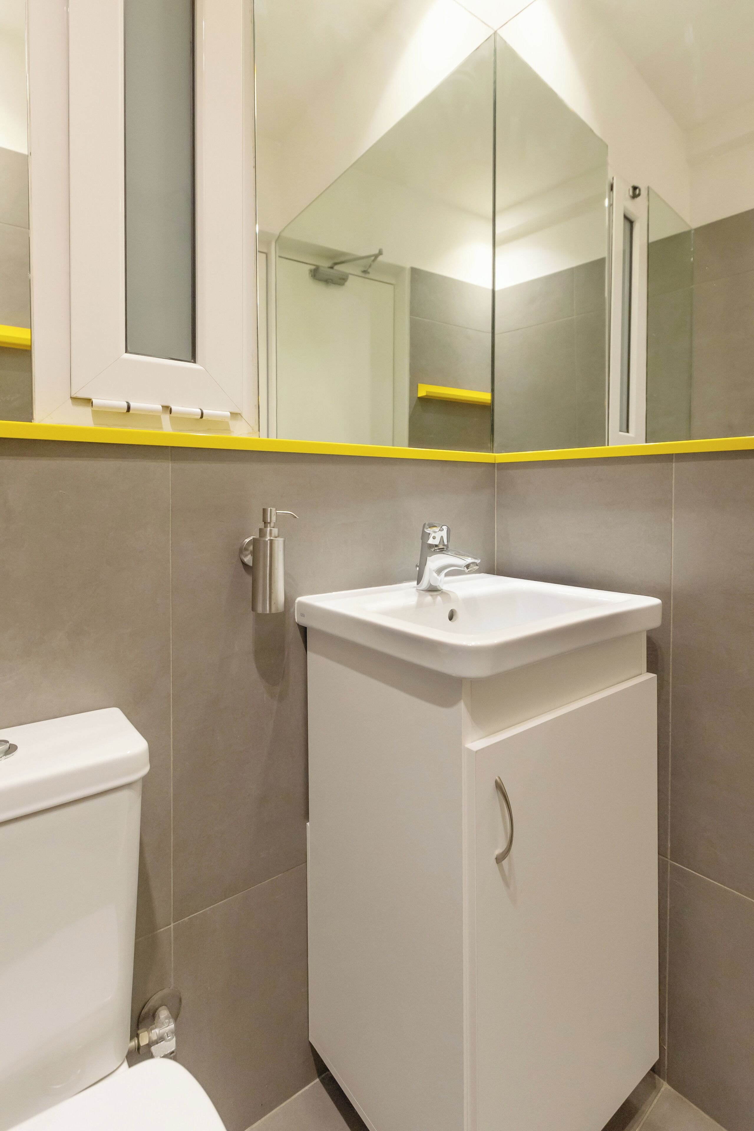 A bathroom with a white sink, a toilet, and a mirror above the sink.