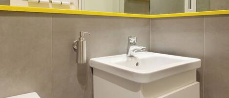 A bathroom with a white sink, a toilet, and a mirror above the sink.