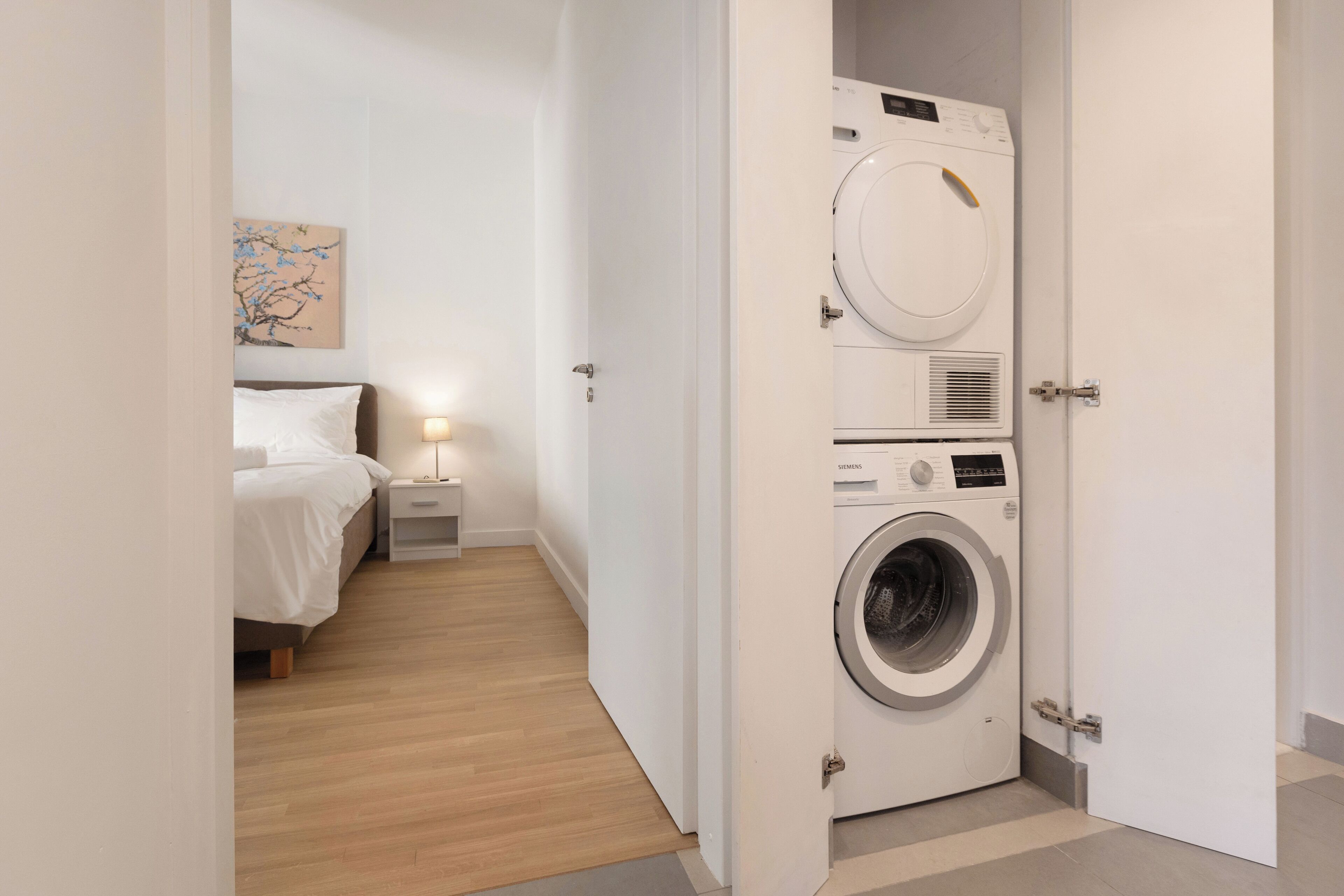 Une chambre d’hôtel équipée d’un lit, d’une table de chevet, d’une lampe et d’une machine à laver.
