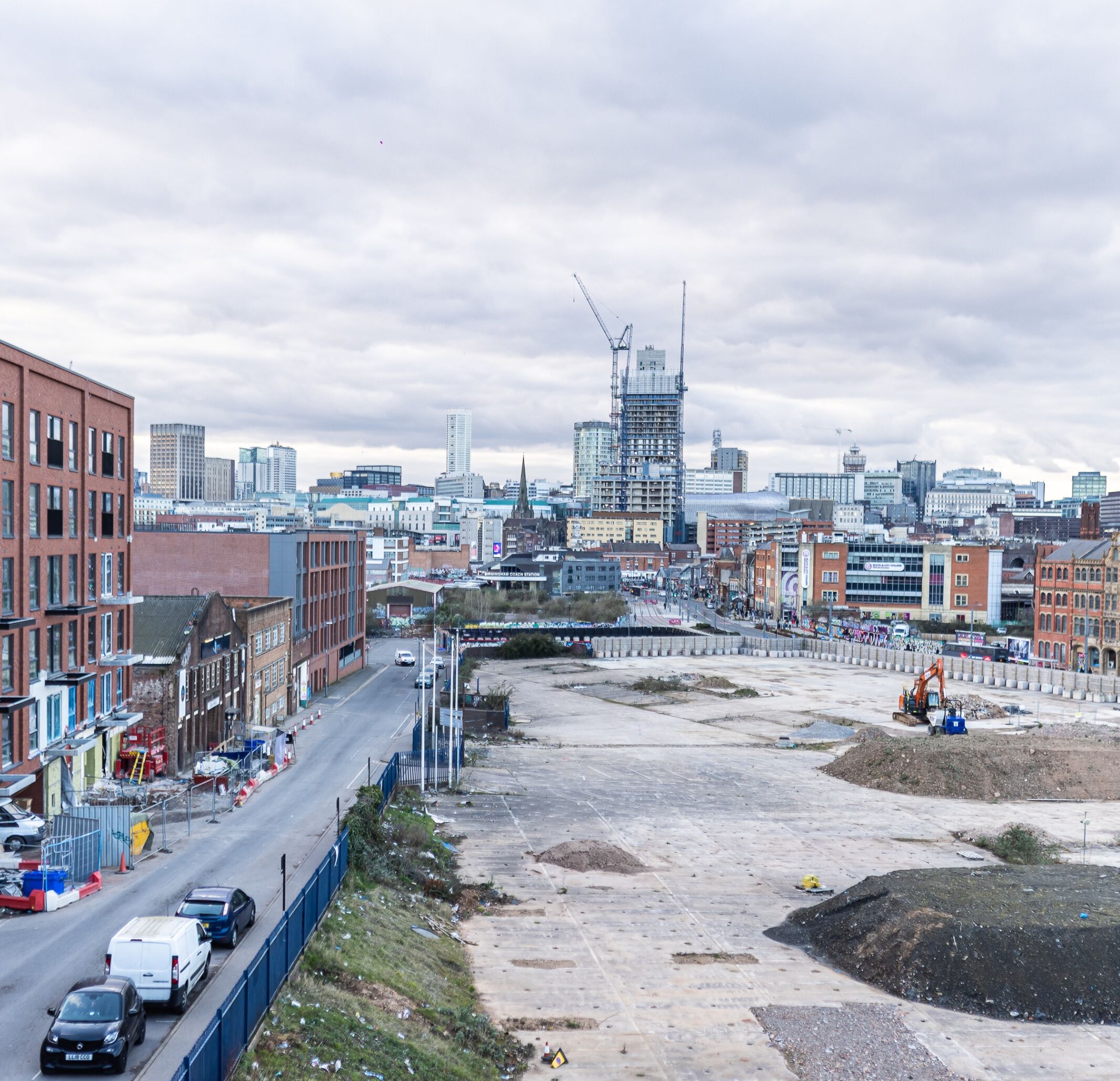 A cityscape with a construction site in the foreground and a mix of modern and historic buildings in the background.