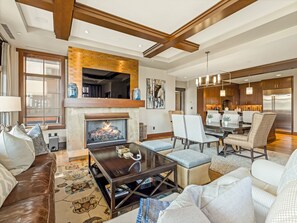 A modern living room with a fireplace, dining area, and kitchen.