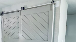 Ein Zimmer mit einer raumhohen Schiebetür im Scheunenstil, hellen Wänden und Holzboden.