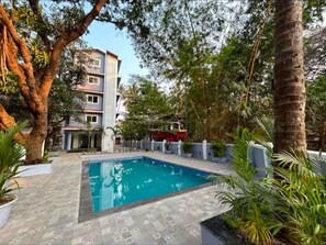Surrounded by lush greenery, this residential area features a central pool and modern buildings with balconies.