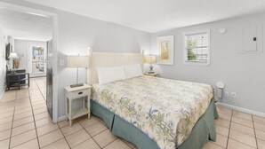 Un dormitorio con cama, mesitas de noche, escritorio y una silla.