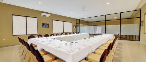 A conference room with a long table, chairs, and a projector screen.