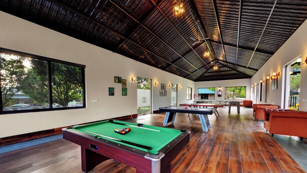 A spacious indoor recreational area with pool tables, wooden flooring, and large windows offering views of the outdoors. - Debu's The Fern Resort & Spa Jim Corbett, Series by Marriott (Ramnagar)