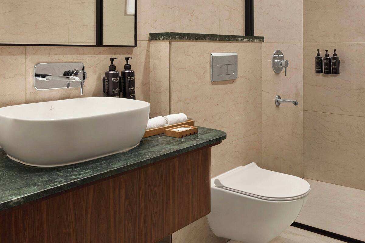 A modern bathroom with a large sink, mirror, and shower.