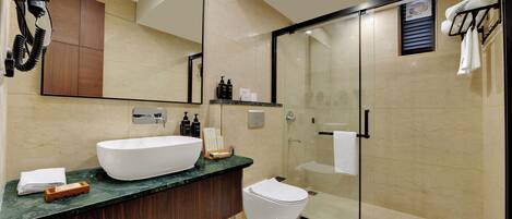 A modern bathroom with a large white sink, dark wood vanity, and a glass-enclosed shower area.